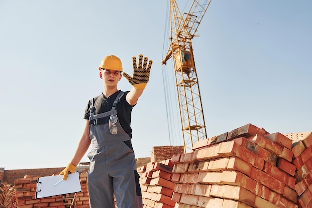 Zeigt Stoppschild von Hand Bauarbeiter in Uniform und Sicherheitsausrüstung haben Arbeit am Bau