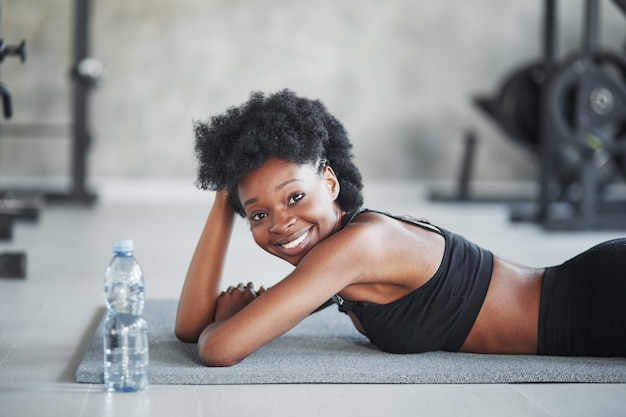 Zeit für den Rest. Afroamerikanerfrau mit lockigem Haar und in sportlicher Kleidung haben Fitness-Tag im Fitnessstudio