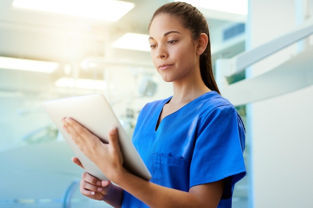 Zeit für eine zweite Meinung Aufnahme einer jungen Krankenschwester, die ein Tablet benutzt, während sie in einer Klinik steht