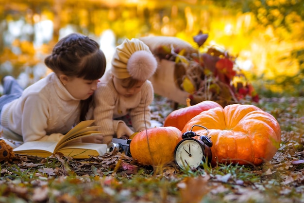 Zeit für Herbstuhr mit Kürbissen auf dem Hintergrund von zwei Schwestern