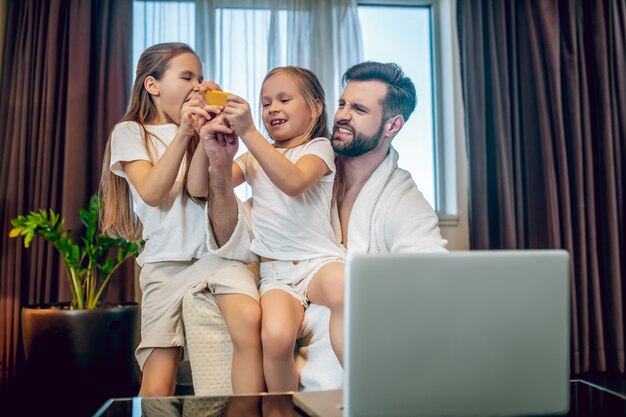 Zeit mit der Familie. Junger bärtiger Mann, der Zeit mit seinen niedlichen Töchtern verbringt