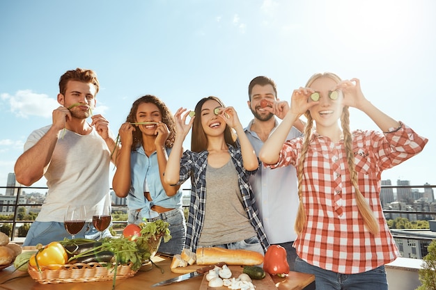 Zeit mit Freunden genießen Gruppe junger und fröhlicher Freunde in Freizeitkleidung, die Essen zubereitet