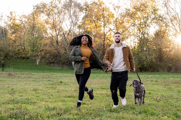 Foto zeit mit ihrem hund junges gemischtrassiges paar verbringt zeit mit haustier draußen