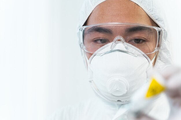 Zeit zu Arbeiten. Aufmerksamer internationaler Forscher mit Maske im Gesicht beim Testen eines neuen Impfstoffs
