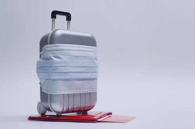 Zeit zu reisen. Das Konzept der sicheren Erholung während einer Pandemie Covid-19 Coronavirus. Koffer für Reisen mit medizinischer Maske und Flugtickets mit Reisepass.
