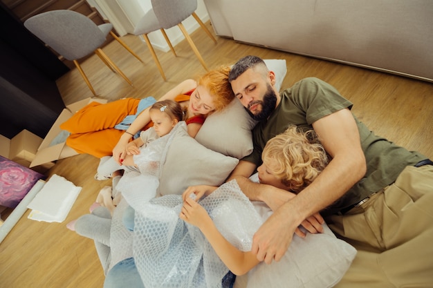 Zeit zum ausruhen. Nette glückliche Familie, die auf Kissen liegt, während sie zusammen im Wohnzimmer schläft