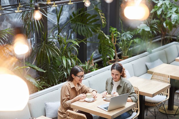 Zeitgenössische Frauen, die Kaffee im Café im Freien genießen