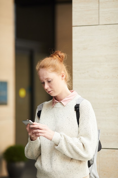 Zeitgenössische junge Frau mit Smartphone im Freien