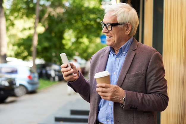 Zeitgenössischer älterer Mann mit Smartphone