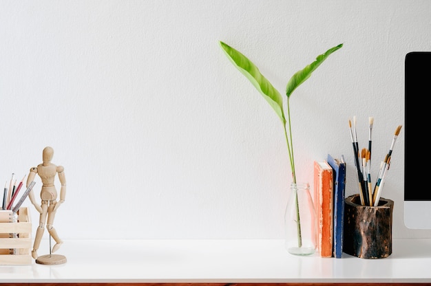 Zeitgenössischer Arbeitsplatz mit Büchern, Farbstiften, Gadgets und Zubehör.