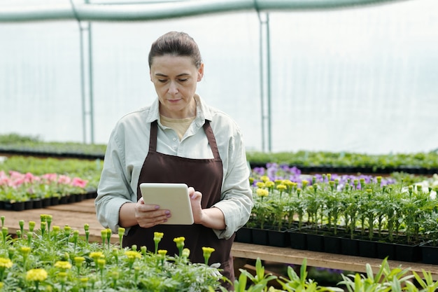 Zeitgenössischer Bauer, der sich Online-Videos über neue Blumensorten ansieht