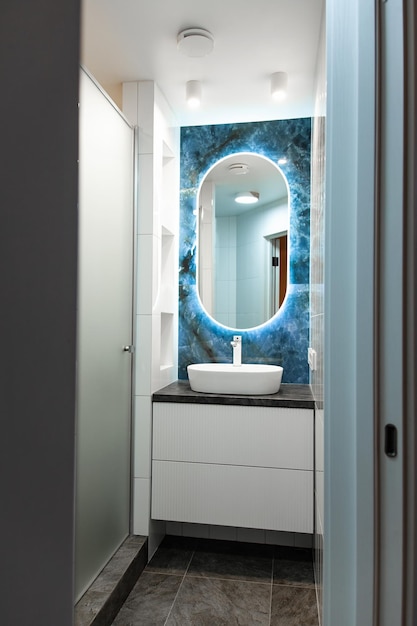 Zeitgenössisches Badezimmerinterieur mit hellem Spiegel und Waschbeckentisch