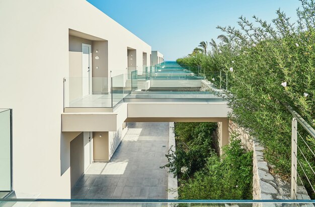 Foto zeitgenössisches hotelgebäude mit großen, leeren terrassen mit glasgeländern in der nähe von grünen bäumen im resort