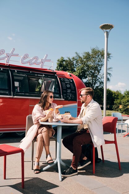 Zeitgenössisches Paar, das sich beim Essen von Fast Food im Café im Freien unterhält?