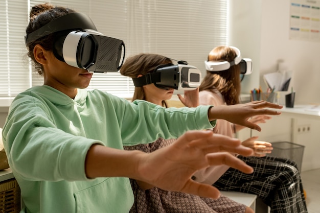 Zeitgenössisches Schulmädchen und ihre beiden Klassenkameraden in VR-Headsets