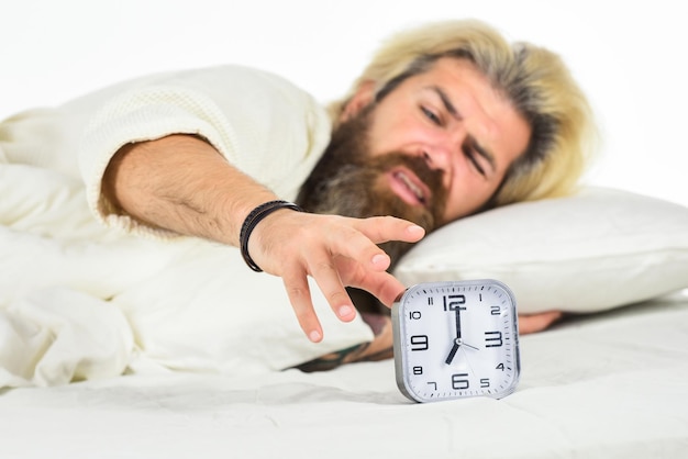 Zeitplan Pünktlich ins Bett kommen Steh sofort auf Gestresster Mann Wecker Hass am frühen Morgen Erwachen Schläfriger Mann und Wecker im Bett Bärtiger Mann mit Wecker Hipster will schlafen