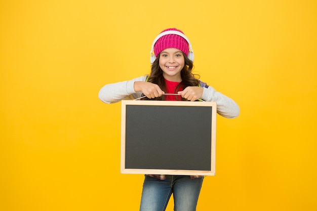 Foto zeitplan und ankündigungskonzept. bildung und entwicklung. technologien zum lernen. moderne technologien. kleines mädchen, das schulbuchkopfhörer hört. sprachen studieren. technologien für das studium.