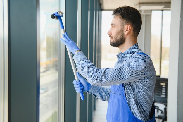 Foto zelador masculino limpando janela no escritório