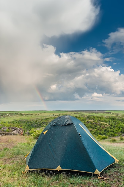 Zelt nach Regen, Landschaft mit Wolken und Regenbogen im blauen Himmel