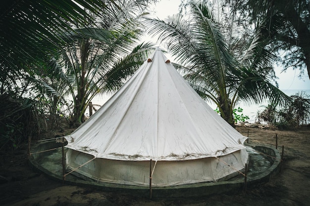 Zelt unter Palmen auf einer tropischen Insel Zelt in Form einer weißen Jurte modernes Wigwam aus Stoff zum Übernachten in der Natur