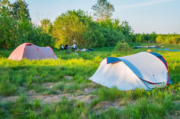 Zeltcamping bei Sonnenuntergang auf der grünen Wiese im Wald