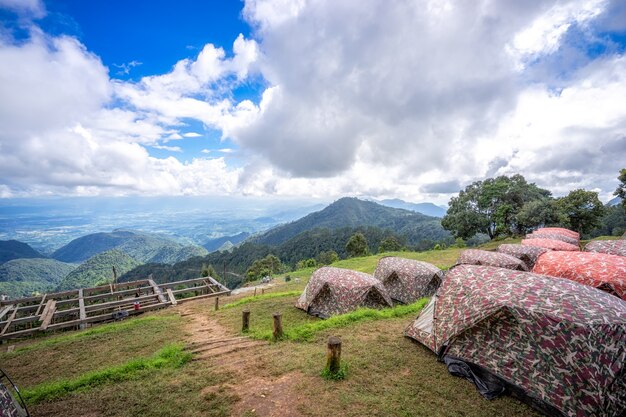 Zelte beim Kampieren unter Wiese mit schöner Landschaft in den Bergen unter Himmel und Clou