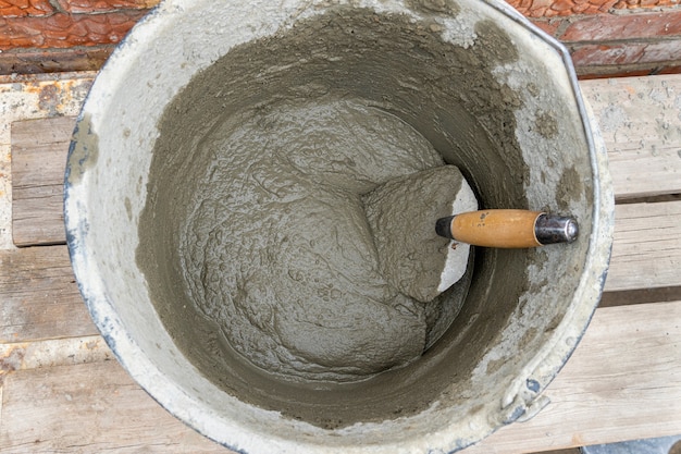 Zement-Sand-Betonmischung in einem Plastikeimer mit einer Kelle