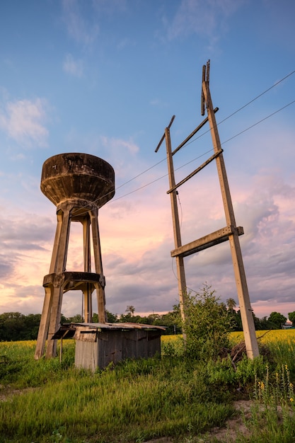 Zementwasserspeichertank und Strommast und Lager auf dem Feld im ländlichen am Abend