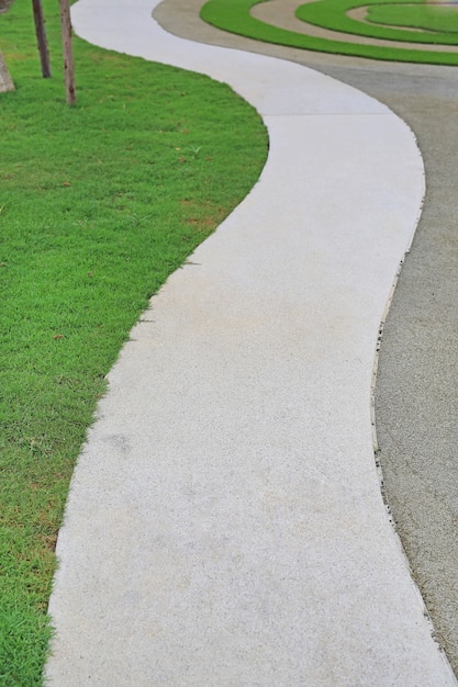 Zementweggehweg mit grünem Gras daneben im Garten