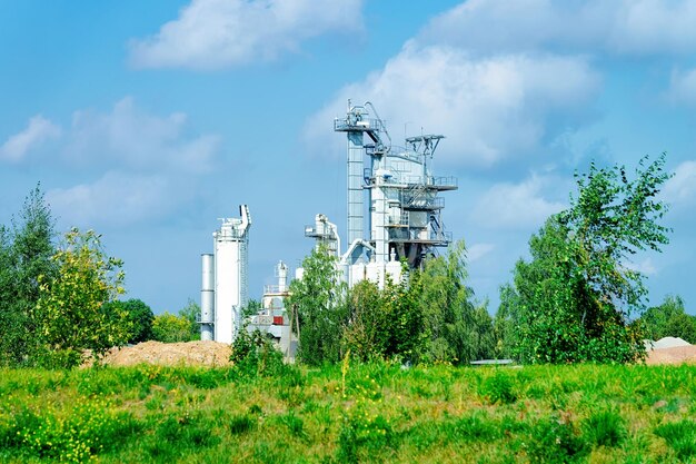 Zementwerk und das grüne Gras. Wolken am blauen Himmel.