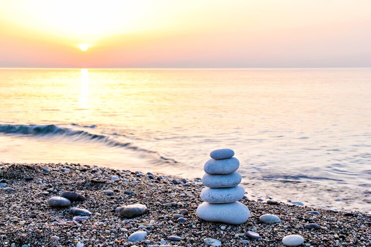 Zen-ähnliche Steinpyramide am Strand bei Sonnenaufgang