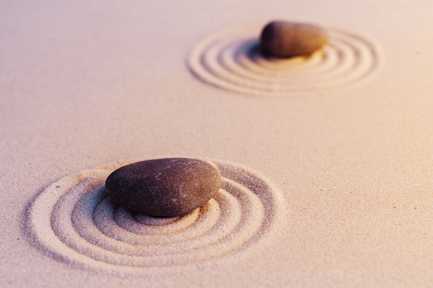 Zen-Gartensteine auf Sand mit Verzierung