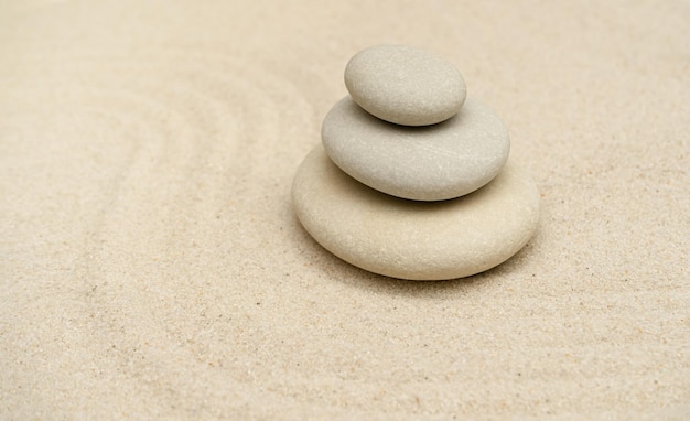 Zen-Steine-Garten Pyramiden aus grauen Zen-Steinen auf dem weißen Sand mit abstrakter Unschärfewelle