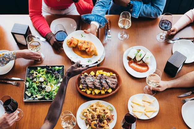 Zenithal-Aufnahme eines jungen schwarzen Mannes, der einem anderen Diner in einem Restaurant einen Teller mit Essen überreicht