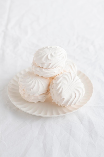 Foto zephyr ou conchas de marshmallow brancas em um prato em uma mesa branca com espaço para texto