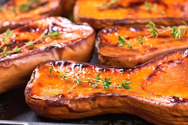 Zerbrochene Butternut-Kürbishälften, gebacken mit Thymian auf einem Backblech, Nahaufnahme