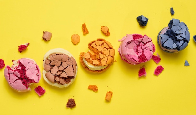 Zerbrochene runde Makronen mit Krümeln auf gelbem Hintergrund, köstliches Dessert, Draufsicht