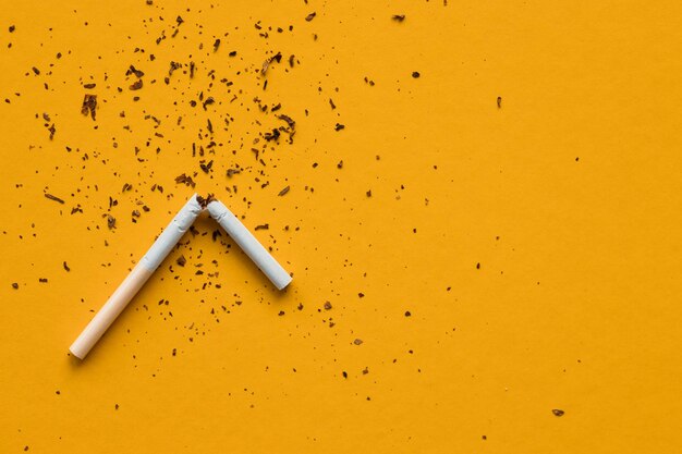 Zerbrochene Zigaretten auf gelbem Hintergrund Rauchen tötetNichtraucherkonzept Kein Tabaktag