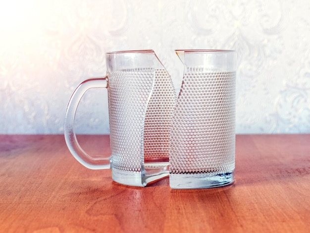 Zerbrochener Glasbecher auf einem Holztisch ein Becher aus zwei Teilen