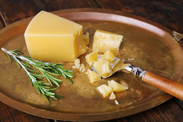 Zerbröckelt Parmesankäse mit Rosmarinzweig und Klinge auf Metalltablett auf Holztischhintergrund