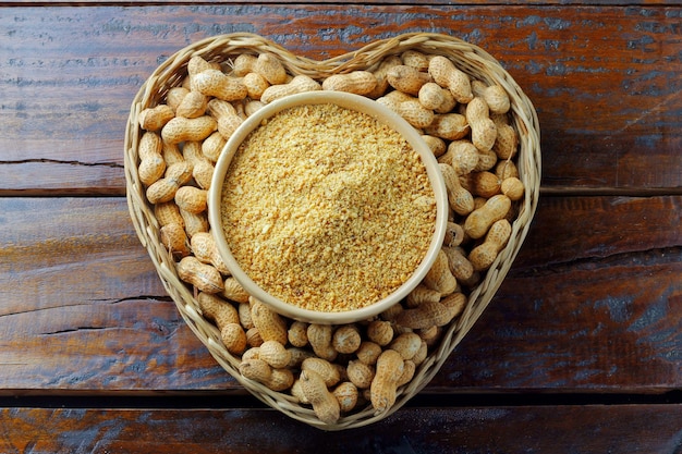 Zerkleinerte und gemahlene Erdnüsse in Keramikschüsseln, die Mehl auf rustikalen Holztisch-Bio-Lebensmitteln bilden