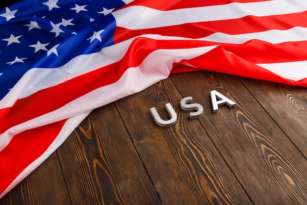 Zerknitterte Flagge der Vereinigten Staaten von Amerika und mit Wort USA auf flachem, strukturiertem Holzoberflächenhintergrund