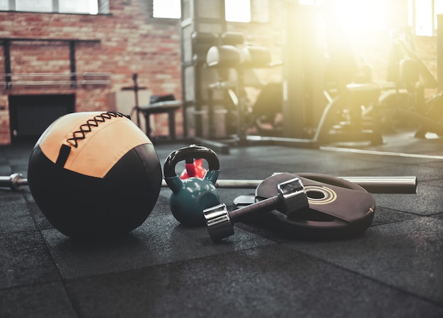 Zerlegte Langhantel, Medizinball, Kettlebell, Hantel auf dem Boden im Fitnessstudio liegend. Sportgeräte für das Training mit freiem Gewicht. Funktionstraining