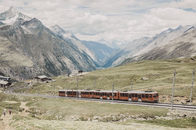 Zermatt, Schweiz - 24. Juni 2017: Gornergrat-Zug mit Touristen geht zum Matterhorn-Berg im Nationalpark Zermatt. Sommerlandschaft, Sonnenscheinwetter, dramatischer blauer Himmel