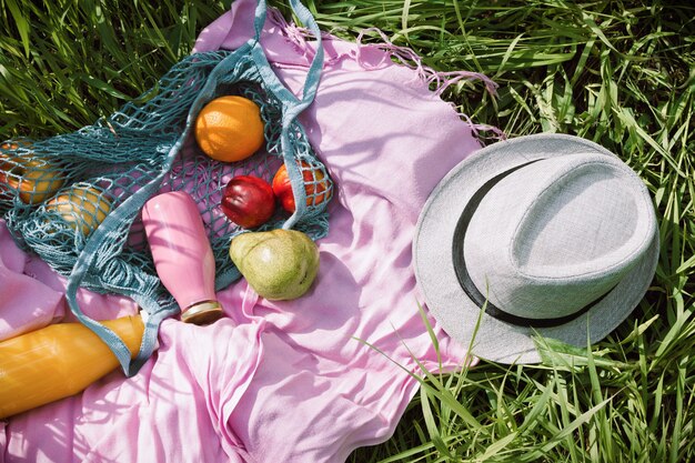 Foto zero desperdício piquenique de verão com frutas frescas e garrafas de suco ou batido no cobertor rosa