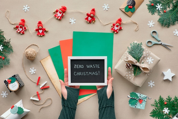 Zero resíduos Natal, apartamento leigos na parede de papel ofício com guirlanda de têxteis, presentes embrulhados, placa preta com o texto "Zero resíduos Natal" em papel de cor. Decoração de Natal verde e ecológica.