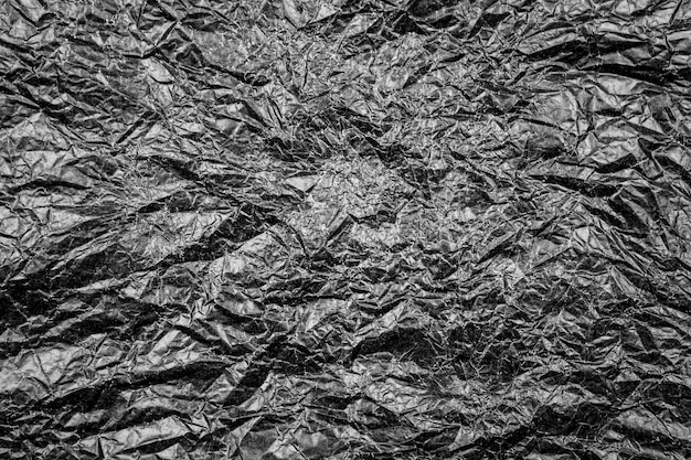 Zerrissene Textur aus dunkelschwarzem, zerknittertem Papier mit Falten