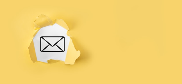 Zerrissenes gelbes Papier mit Brief-E-Mail-Symbol auf weißer Oberfläche