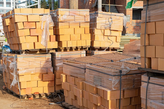 Ziegel in Paletten auf einer Baustelle. Baumaterialien. Roter Backstein für den Bau eines Hauses.