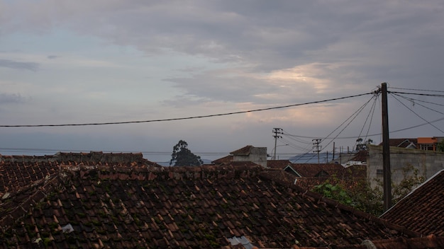 Ziegeldach eines Hauses in einem indonesischen Dorf mit Strommasten am Nachmittag